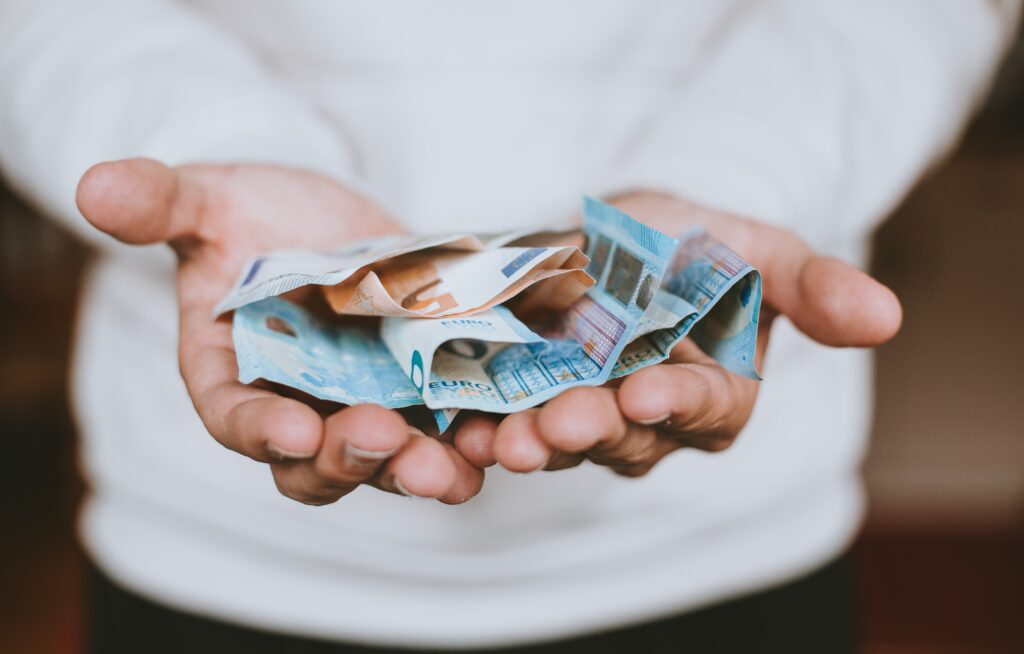 A person holding euro banknotes. The photo is illustrative. Photo by Christian Dubovan on Unsplash.