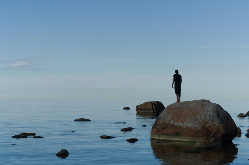 A man standing on a boulder in Lahemaa, Estonia. Photo by transly.eu/Unsplash.