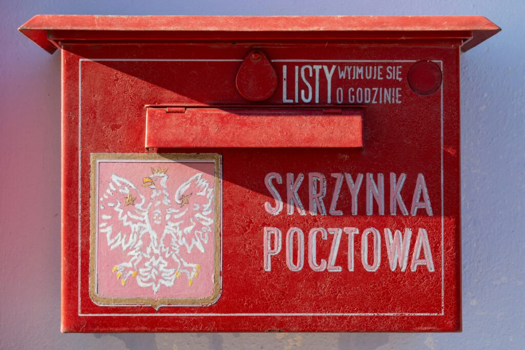 A red Polish postbox, emblematic of a business environment where digital progress still often ends in printed paperwork. Photo by 
Tomasz Zielonka / Unsplash.