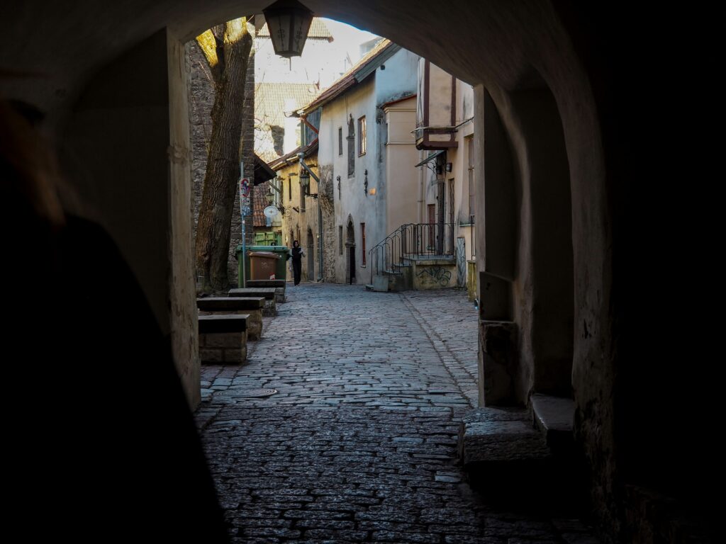 A dark passageway in Tallinn’s Old Town, where ghost stories have echoed for centuries. Photo by Oona Ahonen / Unsplash.