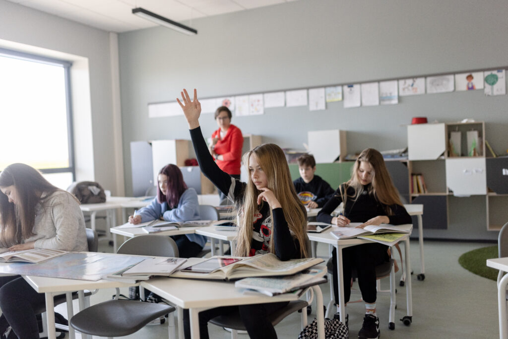 A student raises her hand during a lesson at an Estonian school. Despite the country’s strong PISA performance, 65% of students attend schools where principals say teacher shortages hinder instruction. Photo by Renee Altrov.